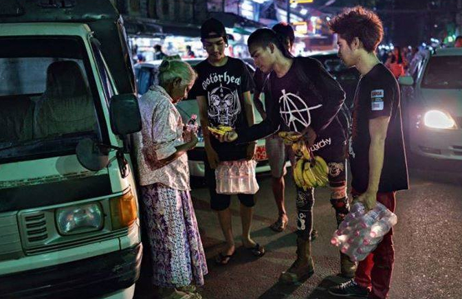 a punk giving food to an older lady